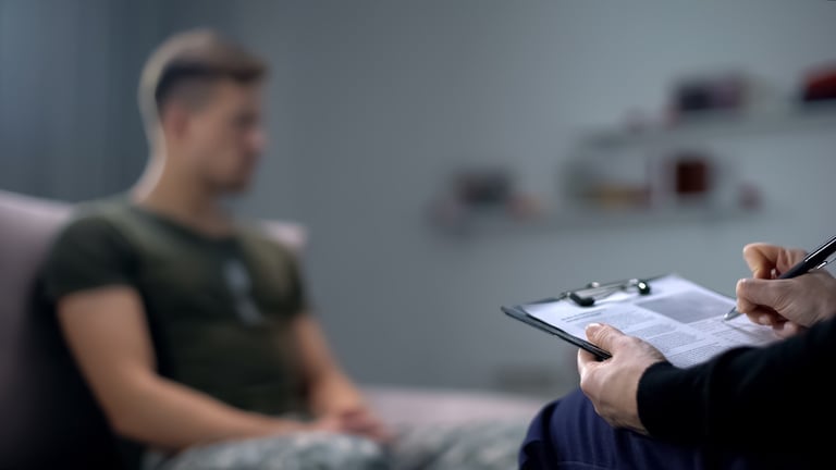 Psychologist Making Notes During Therapy with Male Soldier